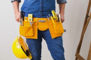 Mid section of handyman with toolbelt and hard hat