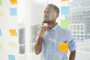 Thoughtful businessman looking at sticky notes on window